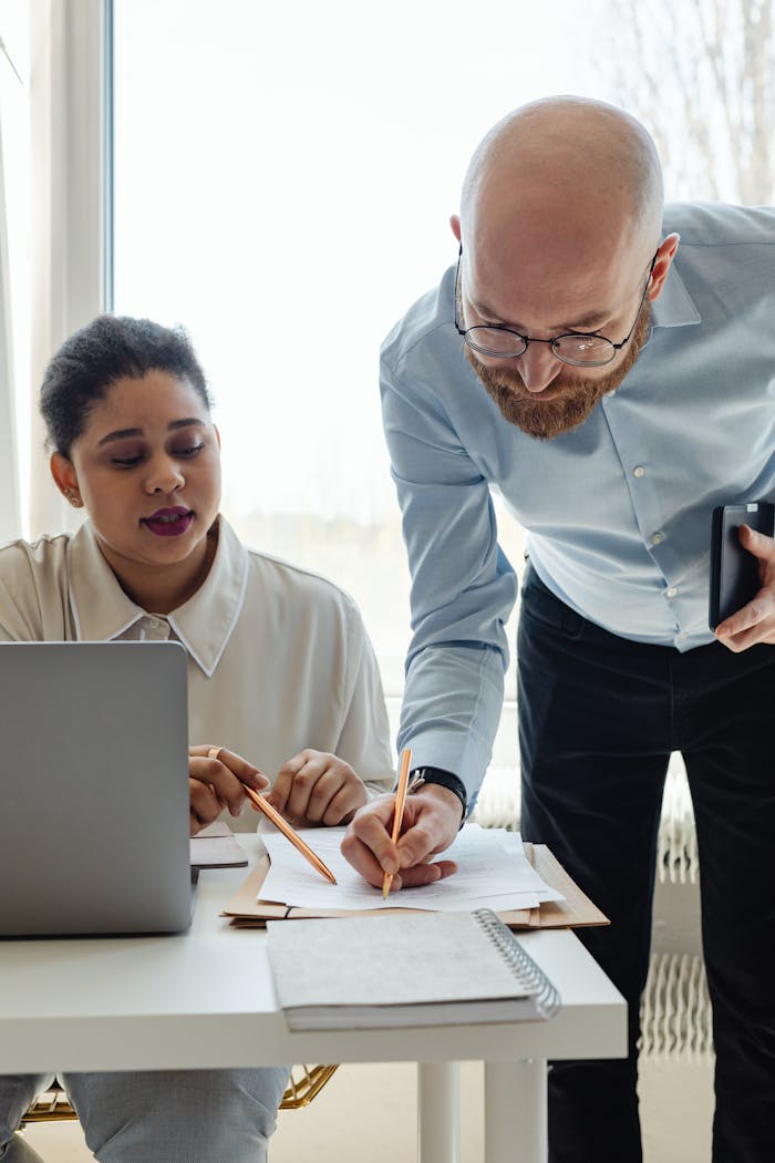 Man in Blue Dress Shirt Discussing Paperwork with a Woman